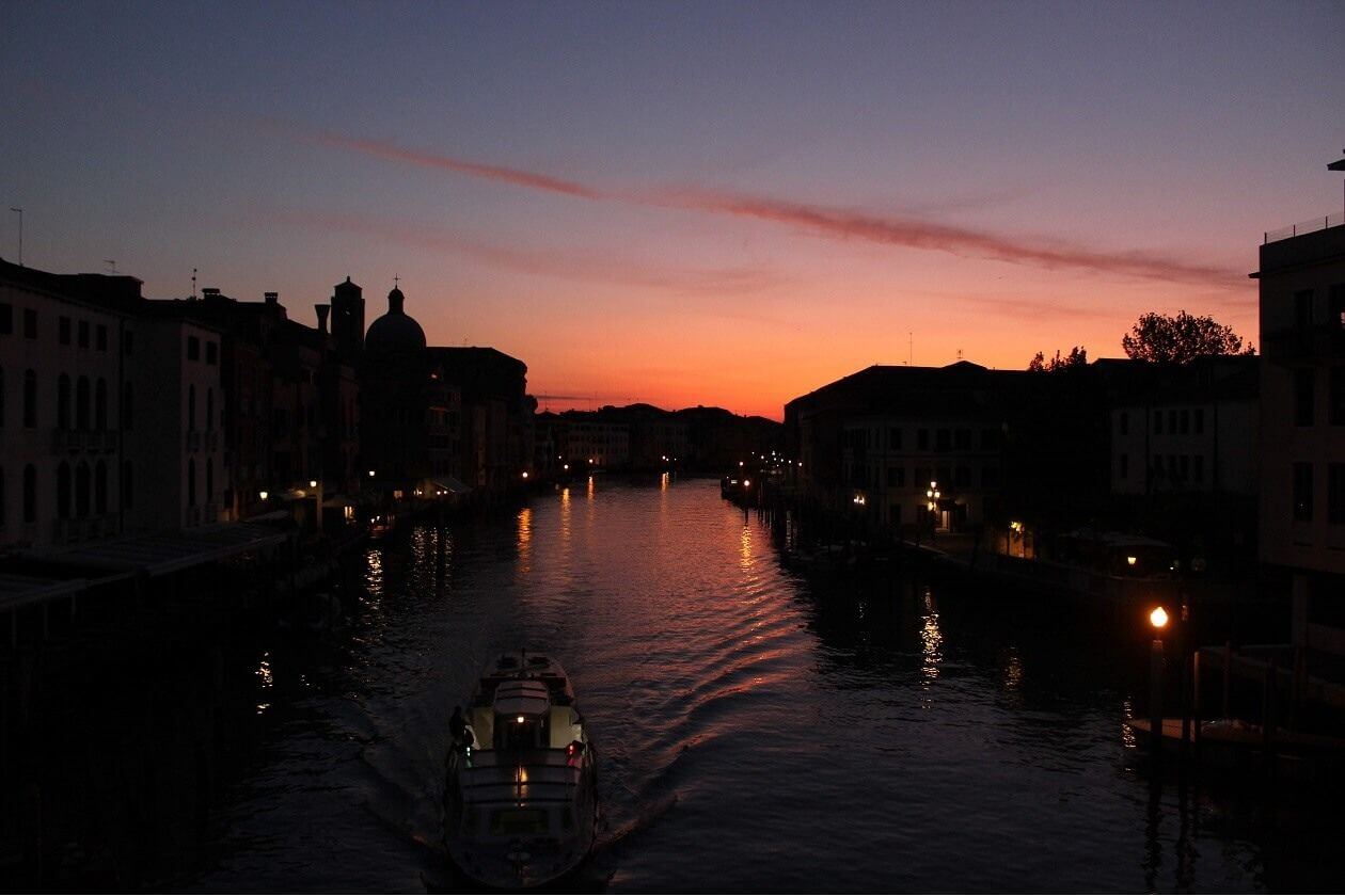 Ein Boot fährt über einen Kanal in Venig bei Sonnenaufgang.