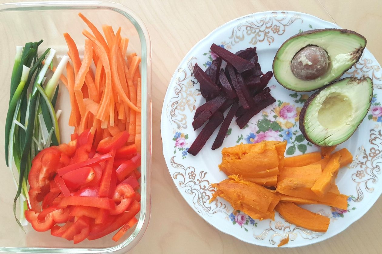 Links eine Schale mit Streifen von Frühlingszwiebeln, Paprika und Möhren, rechts ein Teller mit Rotebeete, Süßkartoffel und einer aufgeschnittenen Avocado.