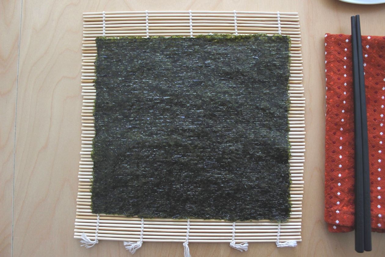 Eine Sushi-Matte mit einem Nori-Blatt darauf.
